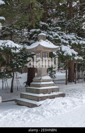 Steinlaterne vor dem Hokkaido-Schrein im Winter. Schnee auf dem Boden. Stockfoto