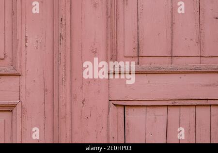 Fragment einer alten Holztür mit rosa Farbe bemalt. Ein Hintergrund von einer alten Oberfläche mit rissiger Farbe. Selektiver Fokus. Stockfoto