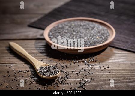 Chia Samen auf Holzplatte und Holzlöffel mit Chia, auf Holzsockel Stockfoto