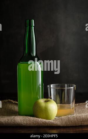 Flasche asturischen Apfelwein mit Glas und Apfel auf dunklem Hintergrund. Stockfoto