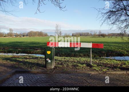 Weidelandschaft im Winter in Nordholland bei Bergen. Wiesen, Bäume, Bauernhöfe, Gräben. Eine Barriere am Ende der Straße. Ein Abfalleimer für Hundekot. Stockfoto