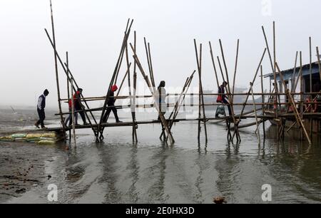 31. Dezember 2020, Guwahati, Assam, Indien: Menschen gehen durch eine Bambusbrücke, um an einem nebligen Morgen in Guwahati Assam Indien am Freitag, dem 1. Januar 2021 an Bord eines Schiffes im Fluss Brahmaputra zu gehen. Der Fluss Brahmaputra ist einer der größten Flüsse Asiens, der aus Chinas Tibet-Region fließt und nach Indien einmündet (Foto: © Dasarath Deka/ZUMA Wire) Stockfoto