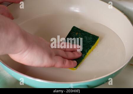 Frau, die eine Bratpfanne mit einem Scheuerschwamm wäscht Stockfoto