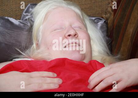 Frau, die unter einem roten Laken auf einer Couch ruht Stockfoto