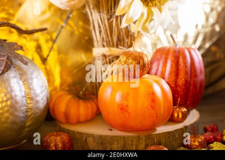 Kleine orange Kürbisse, kleine rote Kürbis, kleine orange Glitter Kürbisse, gelbe, rote und orange Glitter Blätter, silberne Kürbis, und getrocknete Sonnenblumen Stockfoto