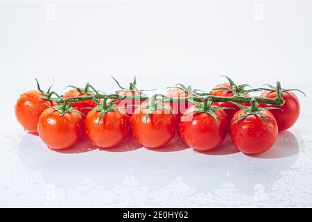 Frische Kirschtomaten auf Ast, isoliert auf weißem Hintergrund. Stockfoto