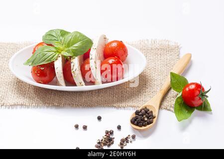 Mozzareela, Tomate und Basilikum, auf weißem Hintergrund. Mediterrane Ernährung und gesunde Ernährung Konzept. Stockfoto