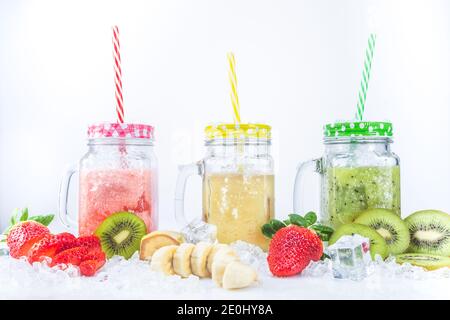Frische Erdbeer-Bananen- und Kiwi-Smoothies, mit Fruchtstücken auf Eis, isoliert auf weißem Hintergrund. Gesundes Ernährungskonzept. Stockfoto