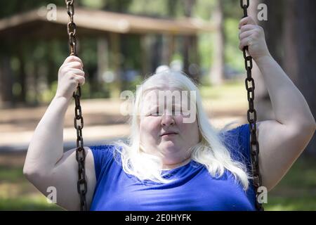 Erwachsene Albino Frau genießen spielen auf einem Park Schaukel Stockfoto