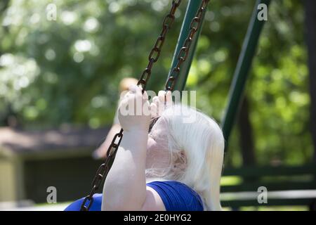 Erwachsene Albino Frau genießen spielen auf einem Park Schaukel Stockfoto