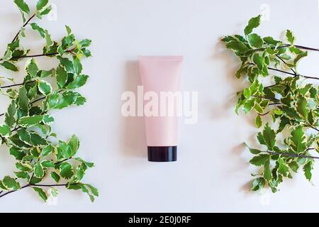 Mock-up von rosa Squeeze Flasche Plastikschlauch mit schwarzer Kappe und frischen Grüns auf weißem Hintergrund. Flasche für Branding und Etikett. Natürliche Bio-Spa Co Stockfoto