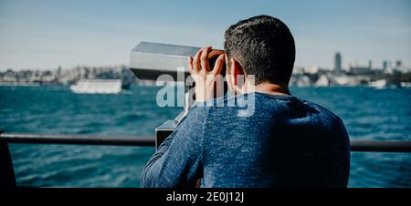 Türkisch gebräunten Kerl schaut auf das Panorama der Stadt Von Istanbul mit Fernglas mit einem Münzempfänger auf dem Banner auf der Promenade der Aussichtsplattform Stockfoto