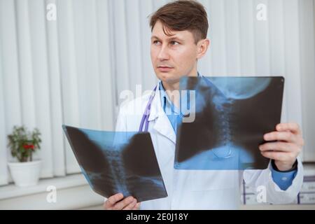Reife männliche Arzt schaut weg nachdenklich, während die Untersuchung Hals Röntgen Scans des Patienten Stockfoto
