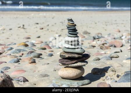 Steine auf dem Meer Sand, Seesteine übereinander gestapelt, eine Pyramide aus flachen Steinen Stockfoto