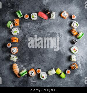 Sushi-Rahmen auf dunklem Hintergrund. Sushi-Brötchen, Nigiri, rohes Lachssteak, Reis und Avocado. Flach liegend. Draufsicht Stockfoto