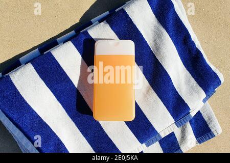 Nachbau aus oranger Plastikflasche ohne Marke und gestreiftem Handtuch. Kosmetische Flasche Behälter für Branding von Medizin oder Kosmetik. Natürliches Bio-Spa. Stockfoto