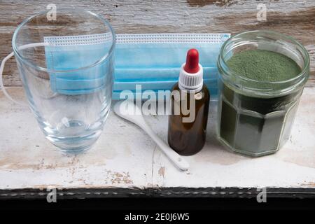 Mundschutz mit Glaslöffel und grünem Superfood-Pulver Stockfoto