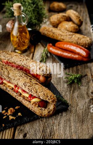 Stillleben Zusammensetzung von leckeren Hot Dogs und Sandwiches mit Verschiedene Beläge und getrocknete Zwiebel auf dunklem Grund Stockfoto