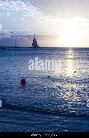 Segelboote bei Sonnenuntergang vom Strand des High Rise Hotels an der Nordwestküste von Aruba aus gesehen. Stockfoto
