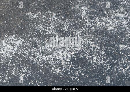 Enteisungsreagenz für Chemikalien auf Asphaltstraßen. Pflaster mit technischem Salz bestreut wird die Straße sicher, Draufsicht machen. Stockfoto