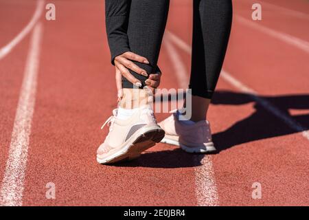 Nahaufnahme einer athletischen Läuferin, die den Fuß wegen verstauchten Knöchels in Schmerzen berührt, Rückansicht. Laufsport, Verletzung durch Training Stockfoto