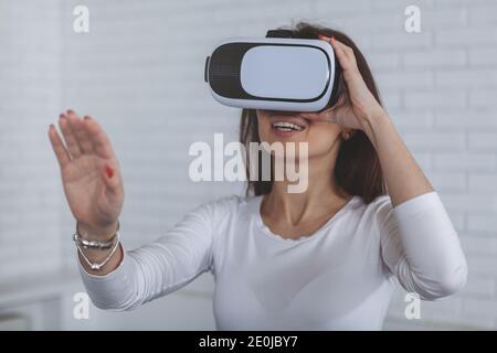 Glückliche junge Frau lächelt, mit der Hand nach etwas streckend, trägt Virtual Reality 3d-Brille. Geschäftsfrau mit vr-Headset bei der Arbeit, Kopie Stockfoto