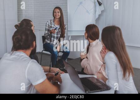 Attraktive Geschäftsfrau, die gerne mit ihren Kollegen spricht und Brainstorming-Meetings in ihrem Büro leitet. Gruppe von Geschäftsleuten, die an einem Projekt arbeiten Stockfoto