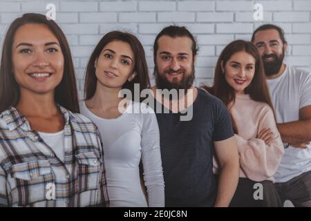 Erfolgreiches Business-Team in legerer Kleidung lächelt zur Kamera, posiert zusammen im Büro. Coworking, Teamwork, Erfolgskonzept Stockfoto