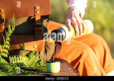 Frau mit Rucksack sitzt auf Holzweg durch Moor Sumpf im Wildlife National Park. Naturforscher ruhen auf der Promenade, trinken Tee, genießen t Stockfoto