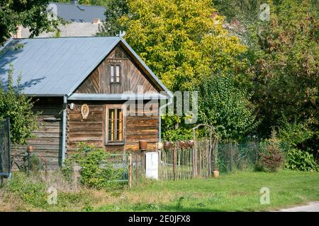 Bescheidene alte Holzhütte in Polen. Umgeben von viel Grün mit Pflanzen und Bäumen. Stockfoto