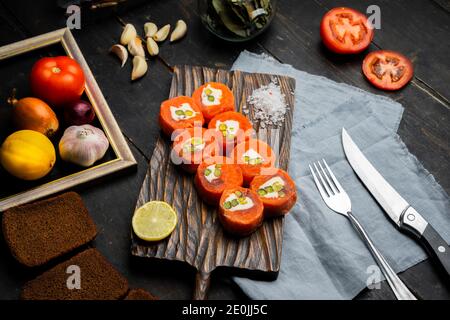 Lachsrollen mit Frischkäse und Pistazien auf einem Holzschneidebrett. Luxus-Catering. Draufsicht. Stockfoto