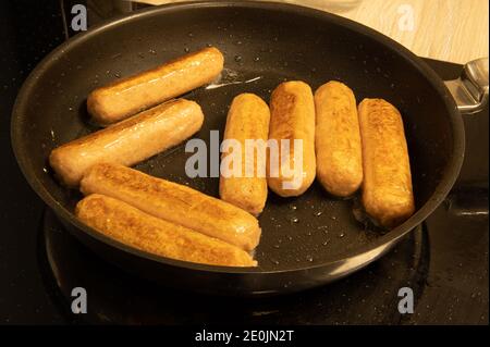 Eine Pfanne mit Würstchen, die in einer Pfanne braten Stockfoto