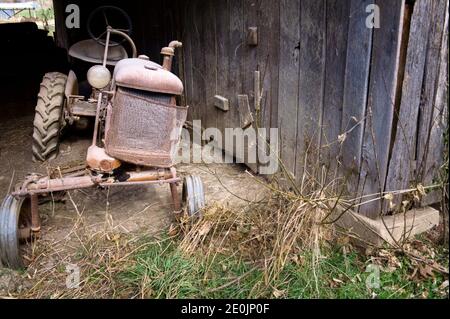 Ein rostiger Oldtimer-Traktor liegt in einem verlassenen Landscheune im Verfall. Stockfoto