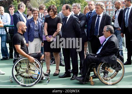 Der französische Präsident Francois Hollande flankierte die französische Sportministerin Valerie Fourneyron und die französische Juniorministerin für behinderte Menschen Marie-Arlette Carlotti trifft den französischen Rollstuhltennisspieler und Paralympischen Olympiasieger Michael Jeremiasz, während er das Trainingszentrum des INSEP (Nationales Institut für Sport und Körpererziehung) in Paris besucht. Frankreich am 16. Juli 2012. Foto von Thierry Chesnot/Pool/ABACAPRESS.COM Stockfoto