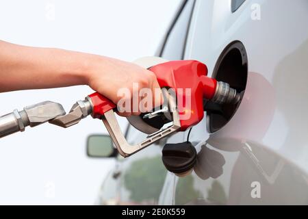 Isolierter Arm und Hand eines jungen Mannes, der Gas pumpt In sein Auto Stockfoto