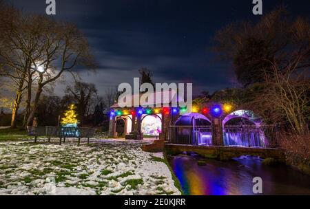 Kidderminster, Großbritannien. Januar 2021. UK Wetter: Alles ist ruhig, da dieser verschneite Neujahrstag zu Ende geht. Eine kalte und trockene Nacht wird für Worcestershire mit Temperaturen unter Null vorhergesagt, bis in die frühen Morgenstunden. Hübsche Weihnachtslichter leuchten hell, ihre bunte Reflexion sichtbar unter einem mondbeleuchteten Himmel in diesem lokalen Park. Kredit: Lee Hudson/Alamy Live Nachrichten Stockfoto