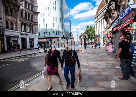 Ein asiatisches Paar mit Masken, das Hand in Hand geht Ein halb verlassenes Central London in der Nähe von Leicester Square während der Sperre Stockfoto