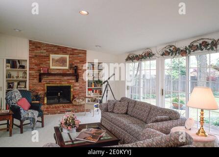 Geräumiges Familienzimmer in Ardmore, OK verfügt über einen Ziegelkamin und eine Fensterwand, 1993, USA Stockfoto