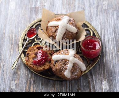 Oster-Kreuz-Muffins mit Rosinen, Preiselbeeren und Himbeermarmelade auf einem Holztisch Stockfoto