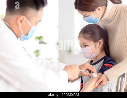 Kinderarzt untersucht Kind und geben Injektion. Coronavirus-Impfung und Covid-19-Impfkonzept Stockfoto