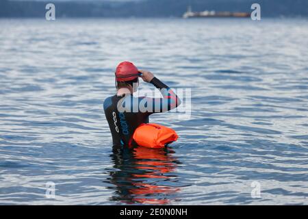 Seattle, Washington, USA. Januar 2021. Ein Schwimmer im Freien bereitet sich darauf vor, beim jährlichen West Seattle Polar Bear Swim im Alki Beach Park in den Puget Sound einzutauchen. Die Organisatoren arrangierten physisch distanzierte Orte und gestaffelte Timing entlang Alki Beach für die Teilnehmer inmitten einer kürzlichen Moderation von COVID-19 Fällen in der Stadt. Quelle: Paul Christian Gordon/Alamy Live News Stockfoto