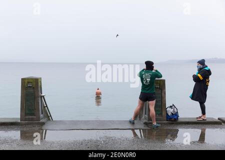 Seattle, Washington, USA. Januar 2021. Mitglieder der berüchtigten Alki Schwimmer Open-Water-Schwimmgruppe sprechen nach dem Eintauchen beim jährlichen West Seattle Eisbären Schwimmen im Alki Beach Park. Die Organisatoren arrangierten physisch distanzierte Orte und gestaffelte Timing entlang Alki Beach für die Teilnehmer inmitten einer kürzlichen Moderation von COVID-19 Fällen in der Stadt. Quelle: Paul Christian Gordon/Alamy Live News Stockfoto