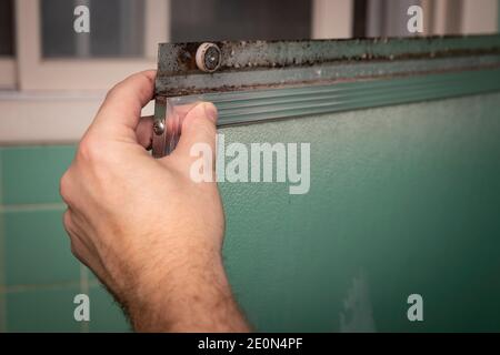 Hand hält schmutzige Schiebeduschtür Rahmen, in Retro-farbigen und Stil Hause Badezimmer Einstellung. Stockfoto