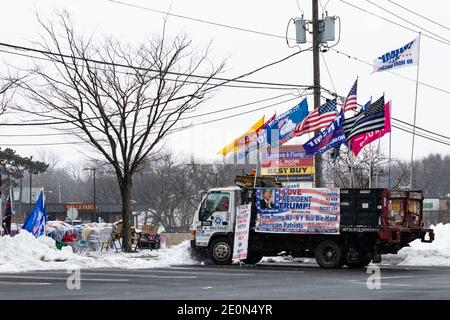 Lange nachdem Donald Trump die Wahl 2020 verloren hatte, schmückt ein Unterstützer seinen Truck mit Pro-Trump-Fahnen und Transparenten und sitzt im Winterschnee am Straßenrand Stockfoto