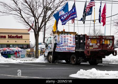 Lange nachdem Donald Trump die Wahl 2020 verloren hatte, schmückt ein Unterstützer seinen Lastwagen mit Pro-Trump- und Anti-Biden-Fahnen und Transparenten und sitzt am Straßenrand in t Stockfoto