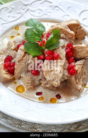 Hähnchensatsivi auf weißem Holzhintergrund mit Granatapfelkernen Stockfoto