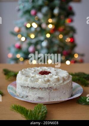 Weißer Kuchen auf dem Tisch mit Weihnachtsbaum im Hintergrund Stockfoto