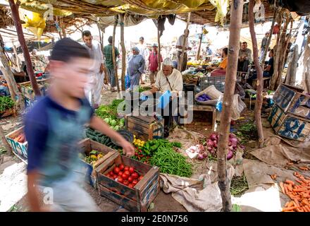 Gemüsehändler mit einem bunten Arrangement von Obst und Gemüse zum Verkauf auf dem Tahanoute Markt im Hohen Atlas von Marokko. Stockfoto