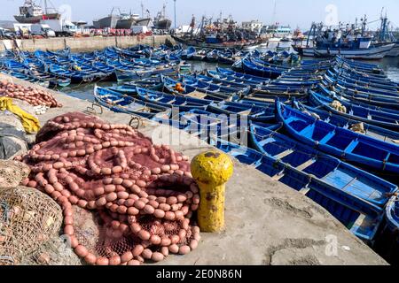 Ein Abschnitt des geschäftigen Fischerhafens in Essaouira in Marokko mit Fischernetzen, kleinen Booten und Trawlern. Der Hafen blickt auf den Atlantischen Ozean. Stockfoto