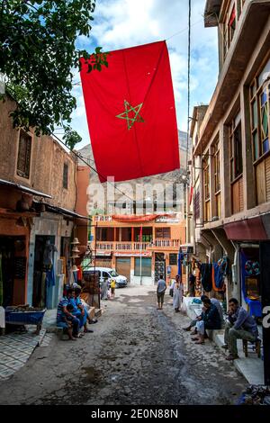 Eine marokkanische Flagge, die in einer Straße im Bergdorf Imlil in Marokko fliegt. Imlil ist ein Dorf im hohen Atlasgebirge von Marokko. Stockfoto